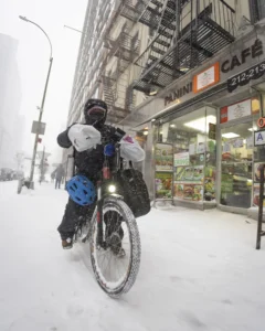 A bicycle courier riding through a city street in winter weather