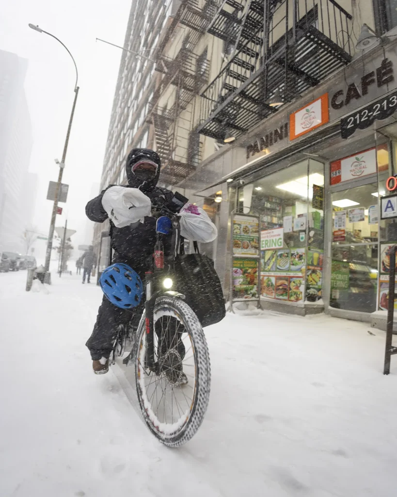A bicycle courier riding through a city street in winter weather